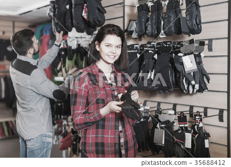 Woman examines the range of protective gloves Woman examines the range of protective gloves 35688412