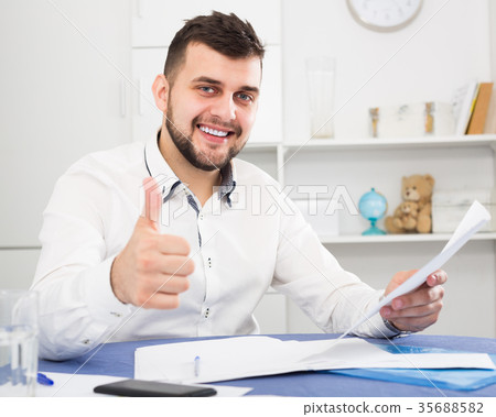Smiling man signing agreement papers at home 35688582