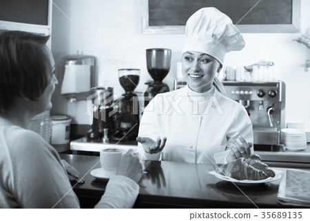 Female cook serving a dessert to the customer in the cafe Female cook serving a dessert to the customer in the cafe 35689135