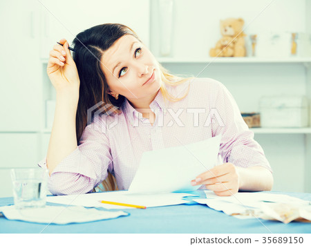 Young woman signing agreement papers at home Young woman signing agreement papers at home 35689150