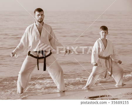 Man and boy perform exercises on karate 35689155