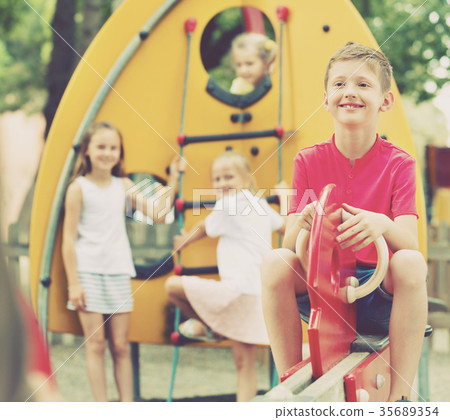 Smiling boy sitting on swing on children's playground Smiling boy sitting on swing on children's playground 35689354