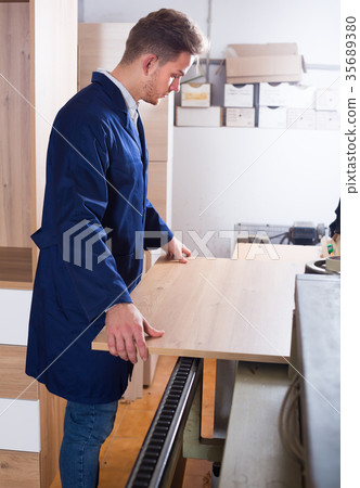 Young male worker adjusting chipboard Young male worker adjusting chipboard 35689380