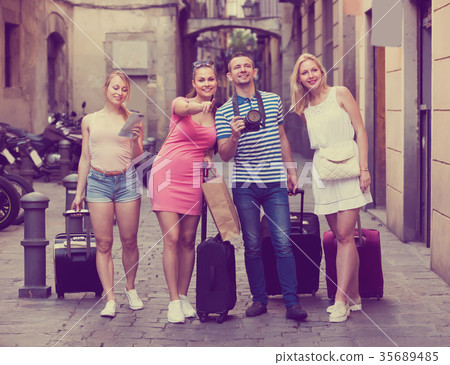 Four glad traveling persons walking in city Four glad traveling persons walking in city 35689485
