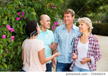 Portrait of mature cheerful males and females talking outdoors 35689834