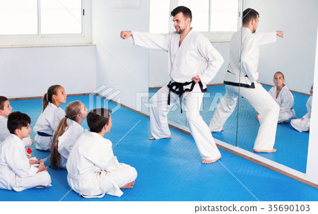 Coach showing new martial moves to children in karate class Coach showing new martial moves to children in karate class 35690103