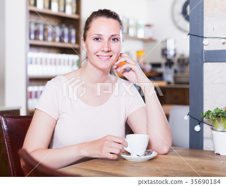 young positive woman resting alone in cafe and drinking coffee young positive woman resting alone in cafe and drinking coffee 35690184
