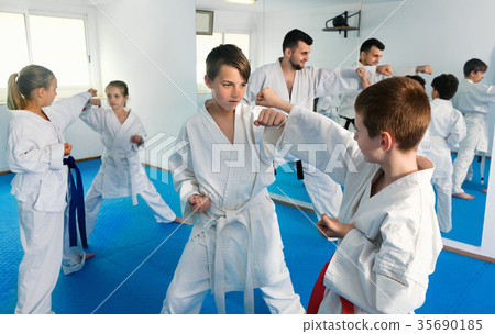 Teenagers practicing new karate moves in pairs in class 35690185