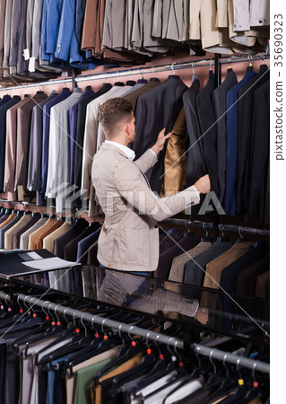 attractive male customer examining men’s suits 35690323