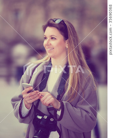 Girl holding phone in hands and looking up her way using app, gps 35690368