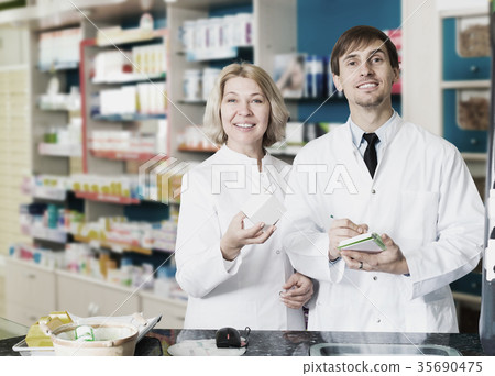 Pharmacist and pharmacy technician posing in drugstore Pharmacist and pharmacy technician posing in drugstore 35690475