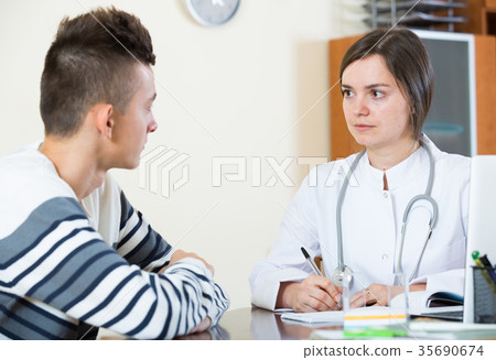 Female doctor questioning teen patient at office Female doctor questioning teen patient at office 35690674