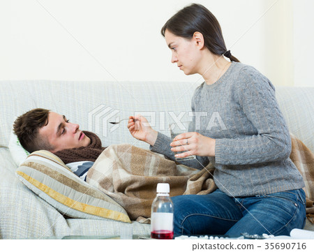 Concerned mother giving mixture to son with quinsy 35690716