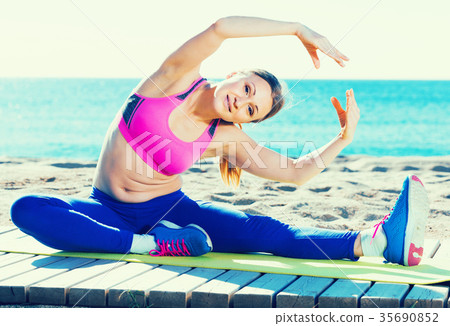 Beautiful female stretching muscles on the sand Beautiful female stretching muscles on the sand 35690852