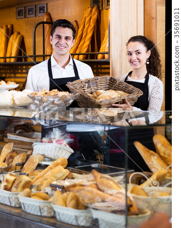 Bakery staff offering bread and different pastry Bakery staff offering bread and different pastry 35691011