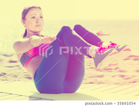 Fitness female stretching muscles on the sand Fitness female stretching muscles on the sand 35691054