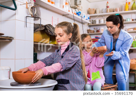 Schoolgirls learning from teacher to make ceramics 35691170