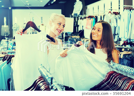 two girls buying tops in clothes store . 35691204