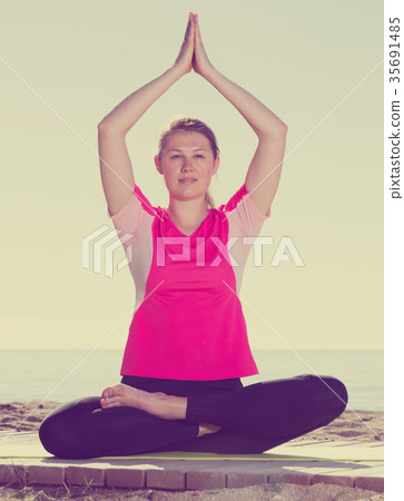 Woman exercising yoga poses on beach 35691485