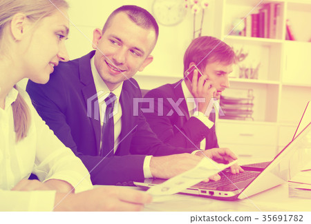 Laughing coworkers working and talking on phone Laughing coworkers working and talking on phone 35691782