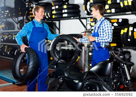 Two male professionals standing with new tires Two male professionals standing with new tires 35692092