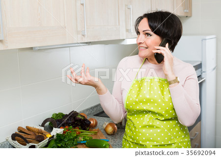 Housewife with phone at kitchen . Housewife with phone at kitchen . 35692094
