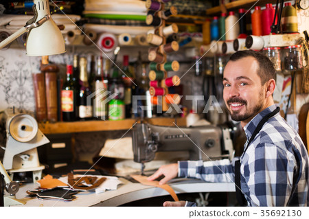 Male worker stitching new belt Male worker stitching new belt 35692130