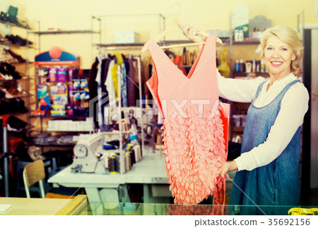 happy mature female tailor having dress in hands in sewing ateli happy mature female tailor having dress in hands in sewing ateli 35692156