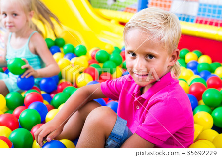boy in elementary school age sitting and playing with multicolored plastic balls 35692229