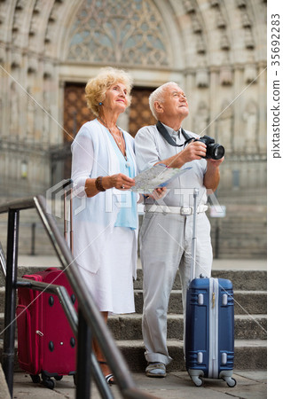 Mature couple making photo and using map during joint vacation 35692283