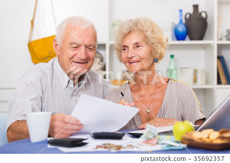 Positive mature couple with papers and laptop 35692357