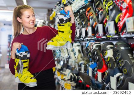 Cheerful female is choosing stylish boots for skiing Cheerful female is choosing stylish boots for skiing 35692490