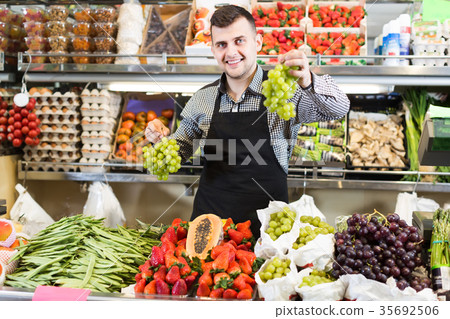 positive male seller showing assortment of grocery shop positive male seller showing assortment of grocery shop 35692506