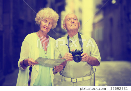 Senior woman and man traveling together looking for destination with city map Senior woman and man traveling together looking for destination with city map 35692581