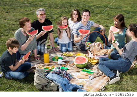 Family with children talking and eating watermelon 35692589