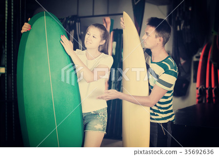 Happy male is showing to female the surfboard Happy male is showing to female the surfboard 35692636