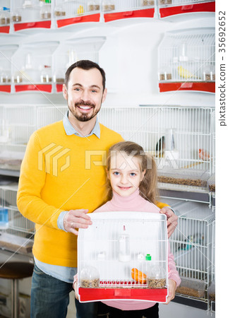 Father and daughter enjoying their purchase of canary bird in pet shop 35692652