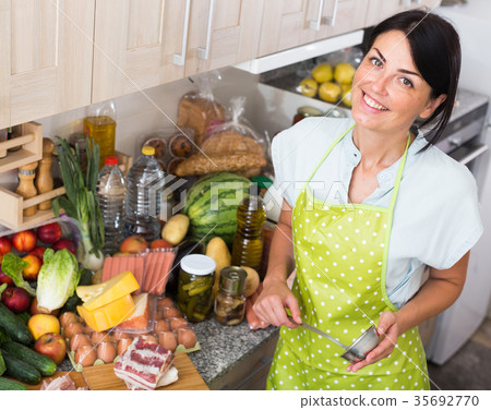 Cheerful woman is posing in time cooking on the kitchen Cheerful woman is posing in time cooking on the kitchen 35692770