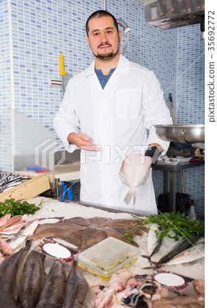 Ordinary salesman in black glove holding fish Ordinary salesman in black glove holding fish 35692772