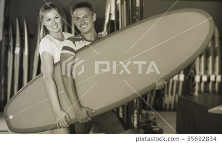 Couple demonstraiting new surfboard Couple demonstraiting new surfboard 35692834