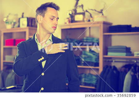 Male customer is trying on new dark blue jacket 35692859