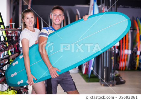 Happy guy with girl buying surfboard Happy guy with girl buying surfboard 35692861