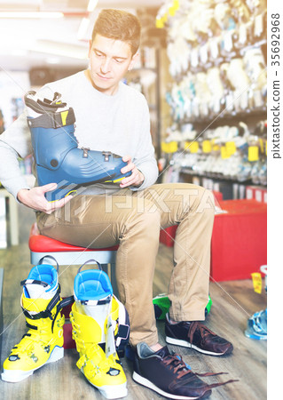 Customer man is trying on new boots for skiing 35692968