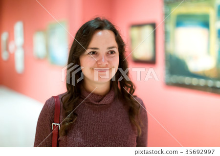 Woman attentively looking at paintings in art museum Woman attentively looking at paintings in art museum 35692997