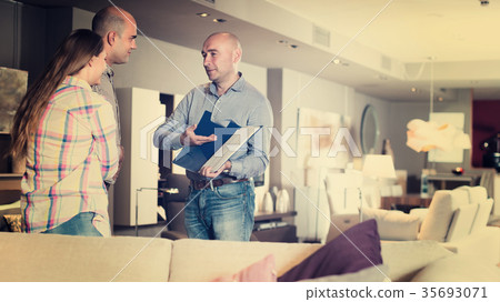 Sales assisstant is showing prices in home furnishings store Sales assisstant is showing prices in home furnishings store 35693071