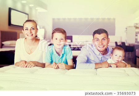 parents with two young sons testing mattress in store 35693073