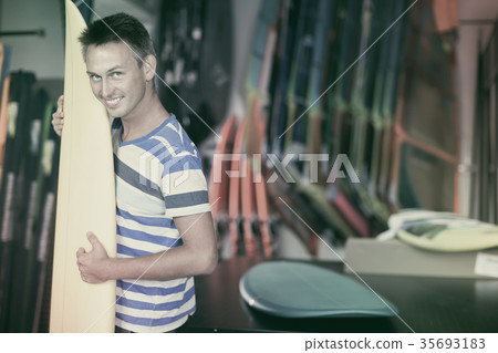 Portrait of laughing guy who is buying surfboard 35693183