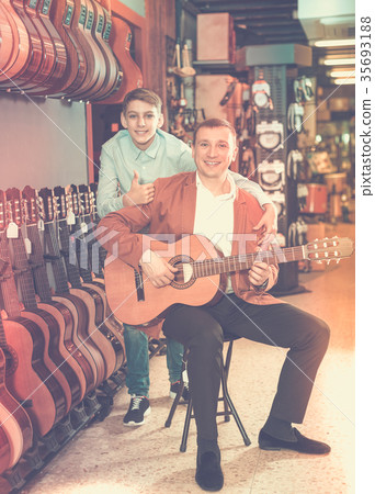 Boy and father choosing acoustic guitar Boy and father choosing acoustic guitar 35693188
