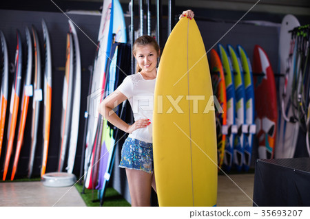 Woman is posing with surfboard in store on the beach. Woman is posing with surfboard in store on the beach. 35693207