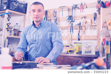young male carpenter working wood plank at workshop young male carpenter working wood plank at workshop 35693223